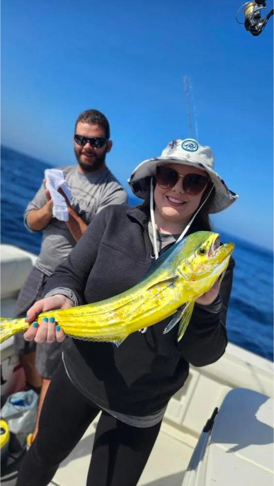 deep-sea-fishing-3 Deep Sea Fishing in San Diego, CA: Woman in hat holding a colorful fish on a boat, with a man standing behind her on a sunny day.